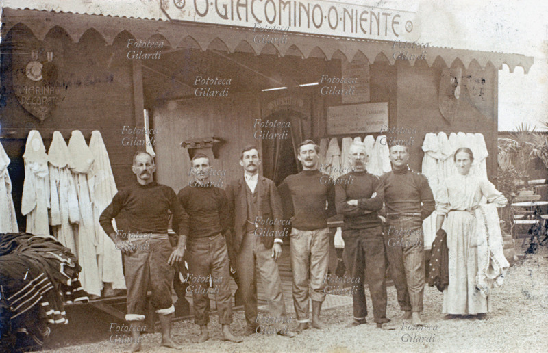 MESTIERI bagnini in posa per i Bagni Giacomino di Pegli (Genova), davanti alla costruzione in legno che accoglie gli organizzatori e le strutture turistiche, sotto la perentoria insegna: \