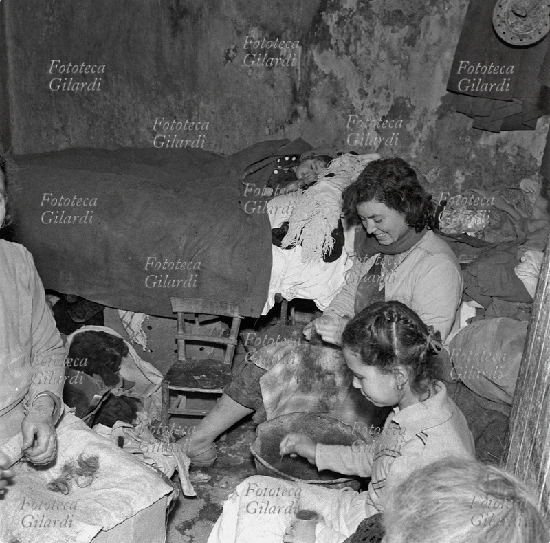 FAMIGLIA donne in casa al lavoro con i bozzoli; tra loro una bambina. L\