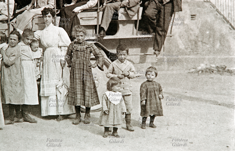 TRASPORTI gruppo di bambini fra le persone riunite in posa per una foto attorno alla diligenza, con i vetturini, i viaggiatori ed alcuni passanti. Fotografia, Italia, primo \