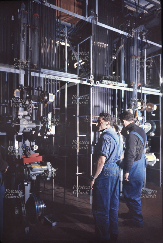 STORIA DEL CINEMA Stampa della pellicola sistema technicolor. Operai addetti alla macchina che volge il negativo in positivo. Fotografia di Ando Gilardi (1921 - 2012) #andogilardi. Stabilimento di Cinecittà. Roma anni 1960
