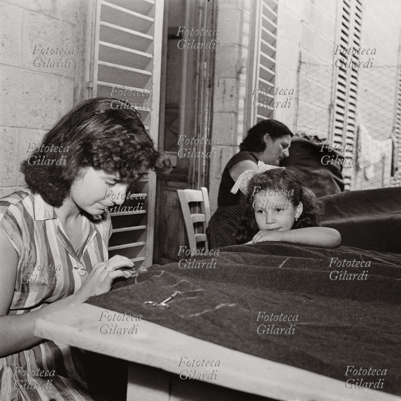 MESTIERI Lavoratrici tessili a domicilio: donne alla cucitura di un tessuto pesante; tempo permettendo, il lavoro veniva svolto all\