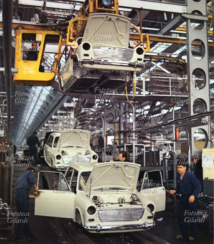 INDUSTRIA Assemblaggio in catena di montaggio della carrozzeria delle automobili Innocenti, mancano ancora tutte le parti meccaniche. Fotografia, Italia 1965 circa. Archivio storico Innocenti.
