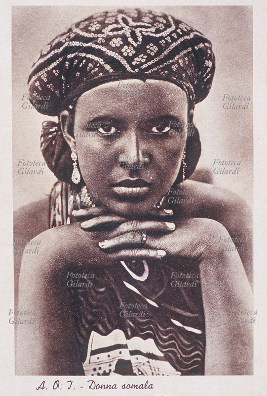 COLONIALISMO A.O.I./Somalia. Donna somala, in posa con le mani incrociate sotto il mento. Cartolina litografica, Mogadiscio s.d.