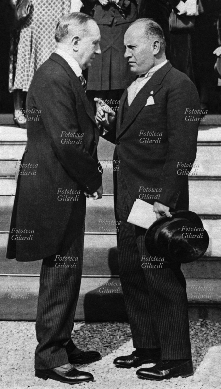 Guglielmo MARCONI (1874-1937) e Benito Mussolini (1883-1945) conversano durante una cerimonia. Ritratti in piedi, di profilo, uno di fronte all\