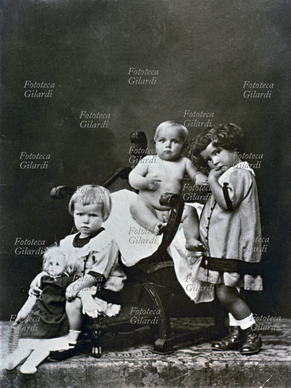 CHILDREN Two sisters with little brother. Well assorted group: a girl and curly brown one with a blonde bob, a bit \