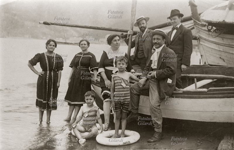 VACANZE Gruppo familiare al mare, composto da tre coppie, in posa per una foto ricordo. Gli uomini della famiglia, vestiti elegantemente con giacca e cappello posano all\