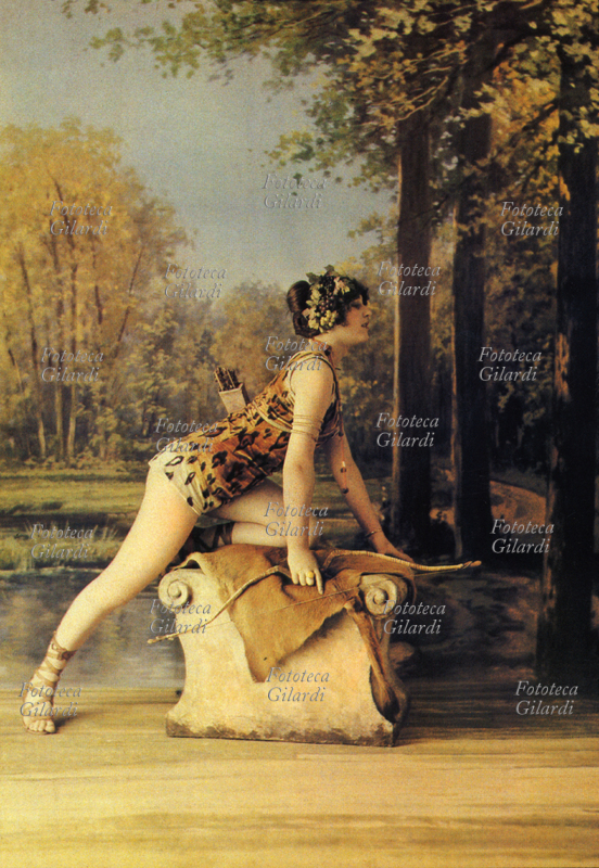 EROTISMO Pin up in veste di Diana cacciatrice; indossa pelle di leopardo e posa con arco e faretra sopra un trono di pietra coperto di pelle d\