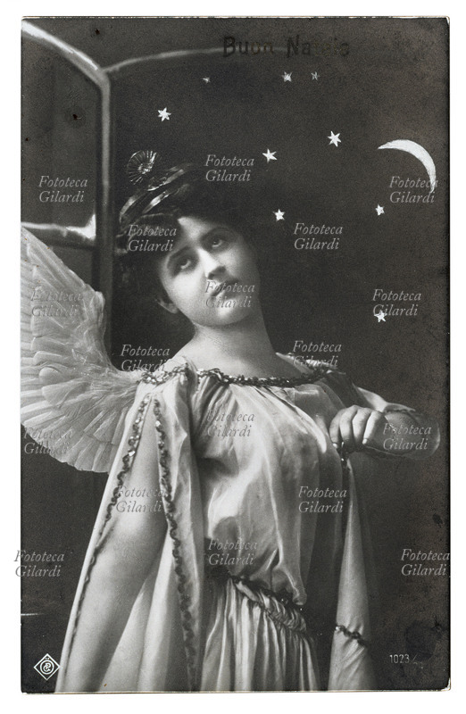 NATALE angelo annuncia la lieta novella. Ritratto a mezzo busto davanti a una finestra aperta sul cielo stellato. Fotografia virata seppia, Italia 1909