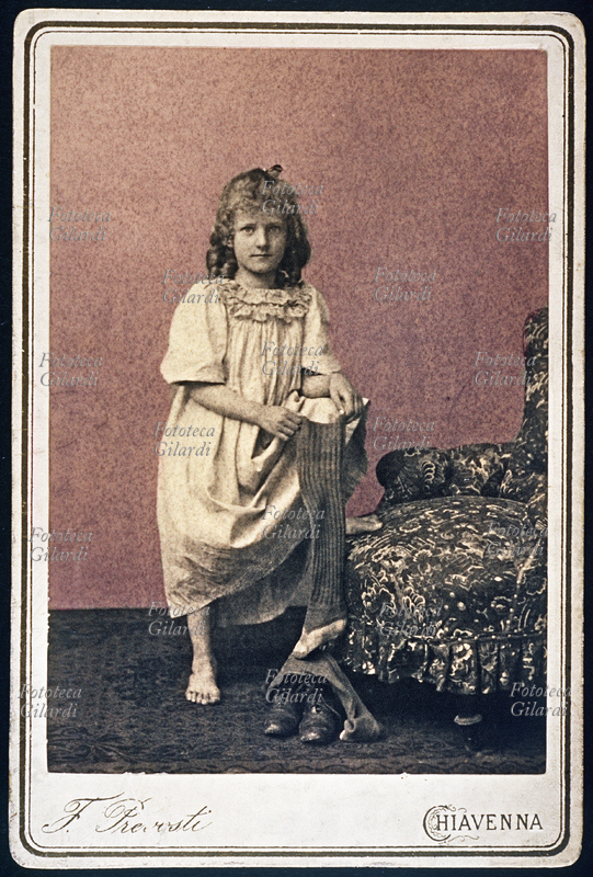 GIRL portrayed in her nightgown, barefoot, holding a long woolen sock. Photography F. Prevosti, Chiavenna, 1890.