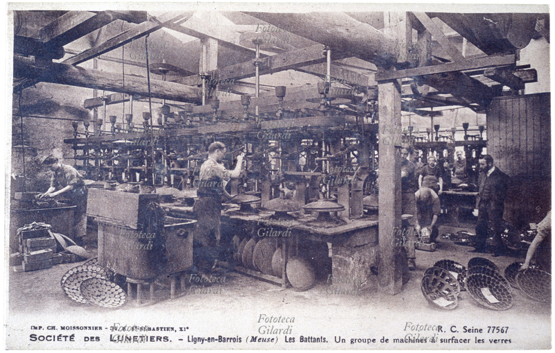 OCCHIALI fabbrica di occhiali francese "Société des Lunetiers - Ligny-en-Barrois (Meuse). Les Battants. Un group de machines à surfacers les verres"; 8, Rue Pastourelle, Paris. Reparto finitura lenti. Cartolina postale promozionale; fotocollografia, Parigi 1928