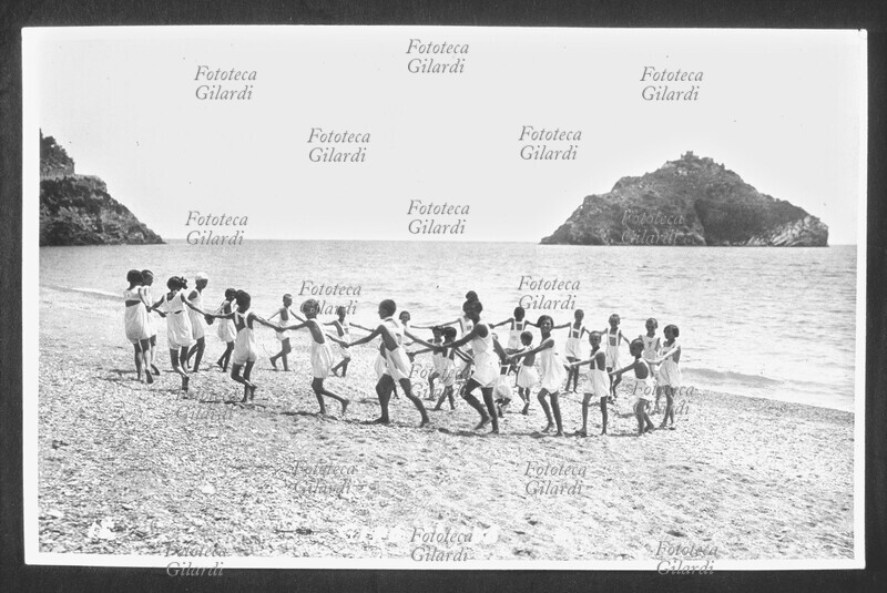 VACANZE Bambini di una colonia marina giocano in girotondo sulla spiaggia. Fotografia, Italia circa 1939.