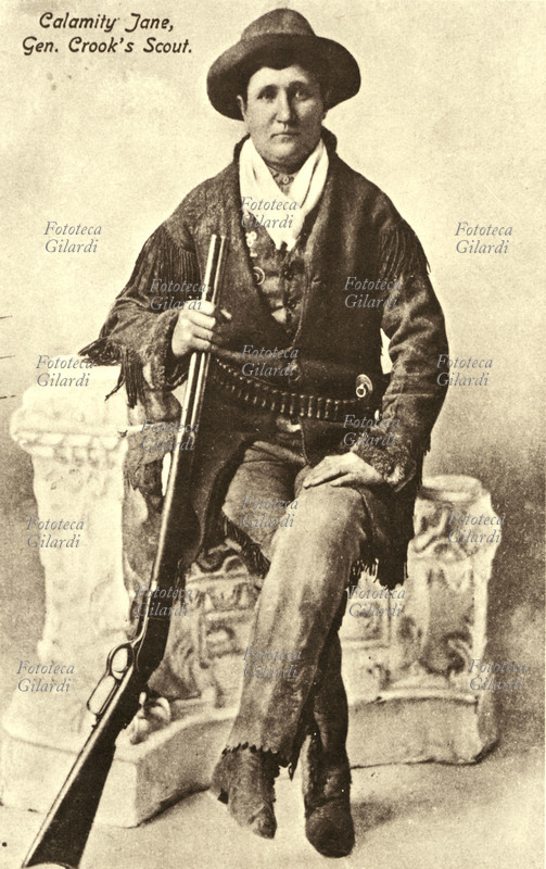 CALAMITY JANE Ritratto fotografico della celebre scout del Generale Crook, che posa seduta con il suo fucile, in giacca e pantaloni di cuoio con a tracolla le munizioni. U.S.A., 1850