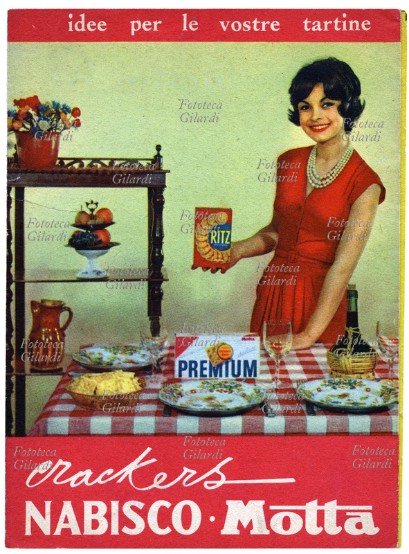 ALIMENTAZIONE crackers Premium e salatini Ritz Nabisco - Motta: una giovane sorridente, vestita con eleganza dietro a una tavola ben apparecchiata, propone gli snack con \