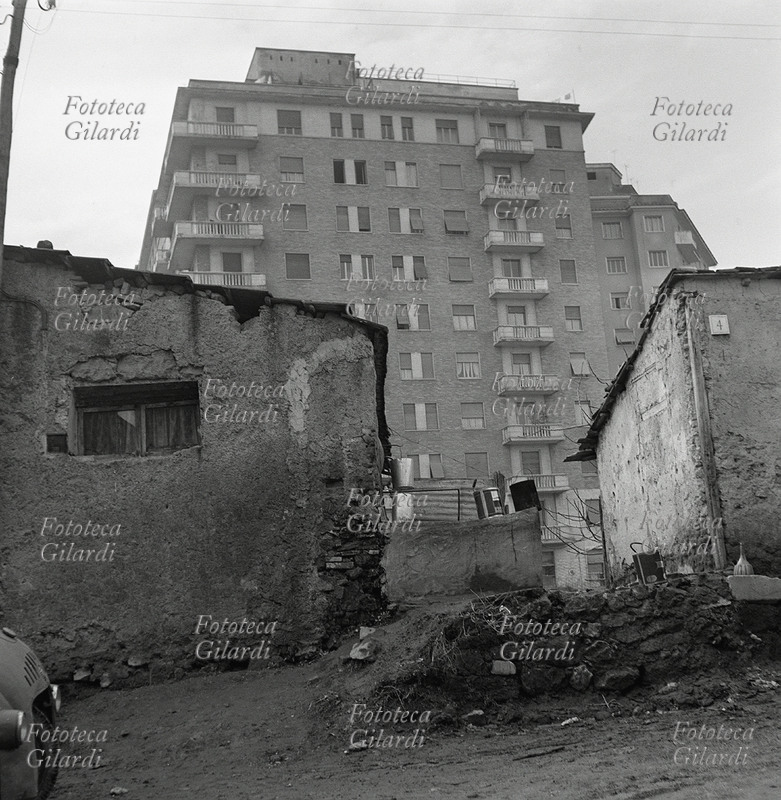 EDILIZIA boom economico: nuove case alla periferia della città, in estremo contrasto accanto al quartiere povero di casette fatiscenti: in primo piano una strada sterrata del vecchio quartiere apre uno scorcio sul nuovo. Fotografia di Ando Gilardi (1921 - 2012) #andogilardi da ampio servizio, Palermo 1957.
