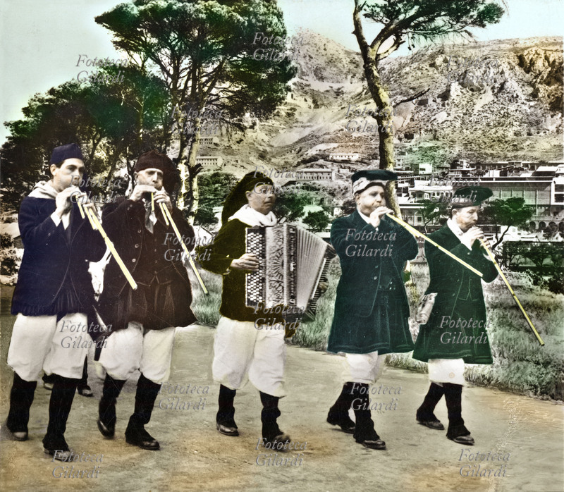 MUSICA POPOLARE Quartu S. Elena (Cagliari). Quattro suonatori di launeddas accompagnati da una fisarmonica, in costume tradizionale. Fotografia colorata, Sardegna, 1950 circa.