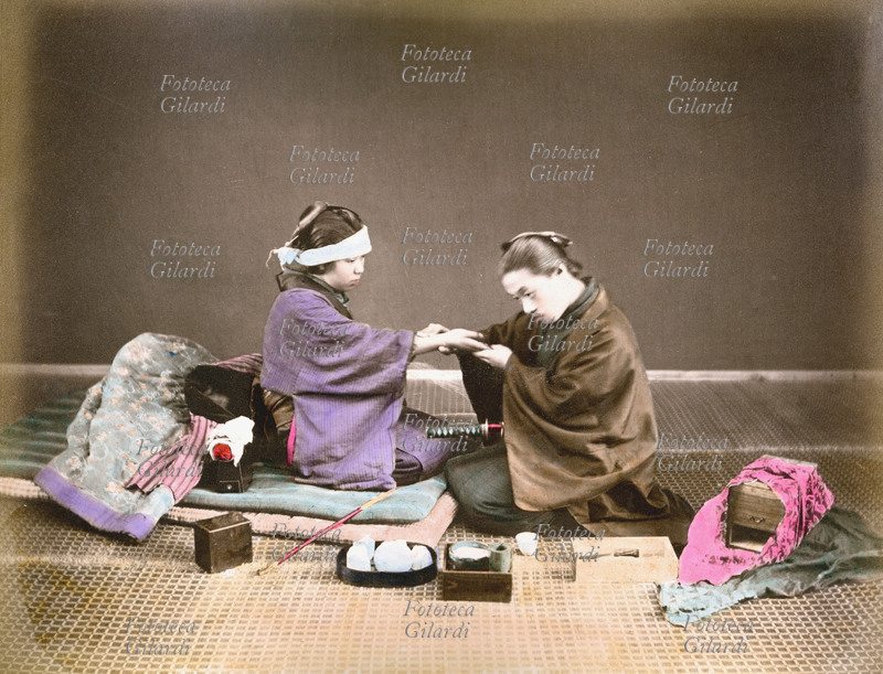GIAPPONE 1890 Guaritore con paziente. Il medico esamina la mano ed il polso della malata, periodo Meiji (1868-1912). Fotografia colorata a mano, 1890 circa.