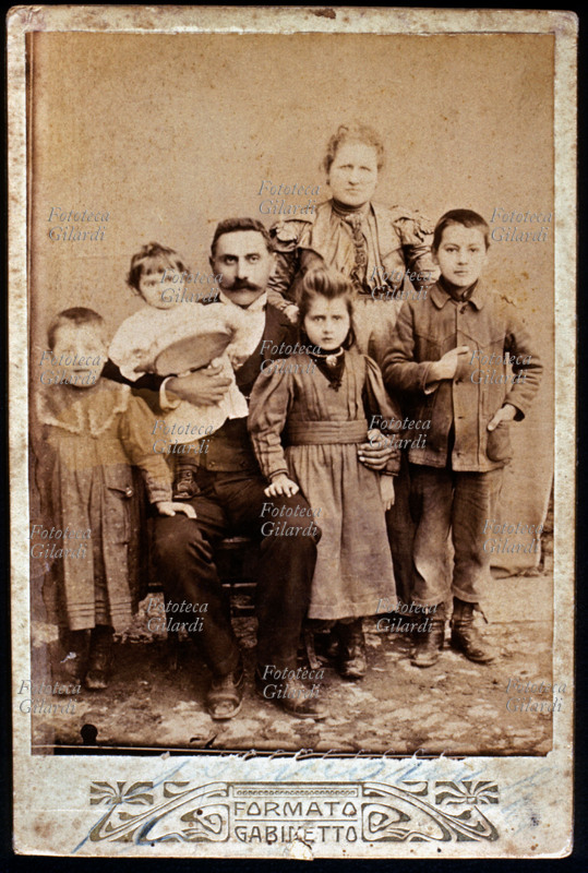 FAMIGLIA genitori e quattro figli bambini, tre femmine e un maschio, in posa. Il fotogruppo è stato preso in studio, davanti ad un fondale bianco uniforme, senza scenografia, La luce naturale proveniente dall\