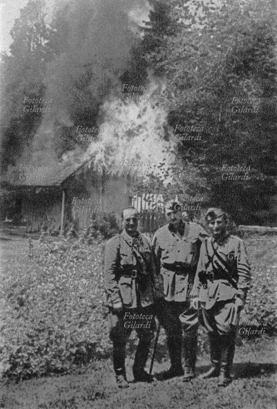 II GUERRA MONDIALE Soldati italiani posano per una foto ricordo davanti alle case di un villaggio da loro incendiato. Iugoslavia 1942