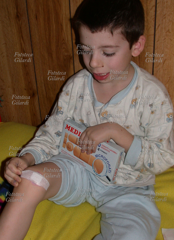 MEDICAZIONE Bimbo stacca il cerotto che protegge una piccola ferita sul ginocchio.