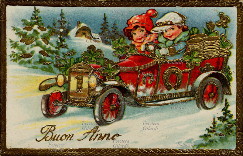BUON ANNO coppia di bambini sorridenti lo augurano sfrecciando sulla loro automobile rossa decorata con simboli della buona fortuna: grandi quadrifogli verdi e ferri di cavallo dorati. Cartolina augurale, Italia 1933.