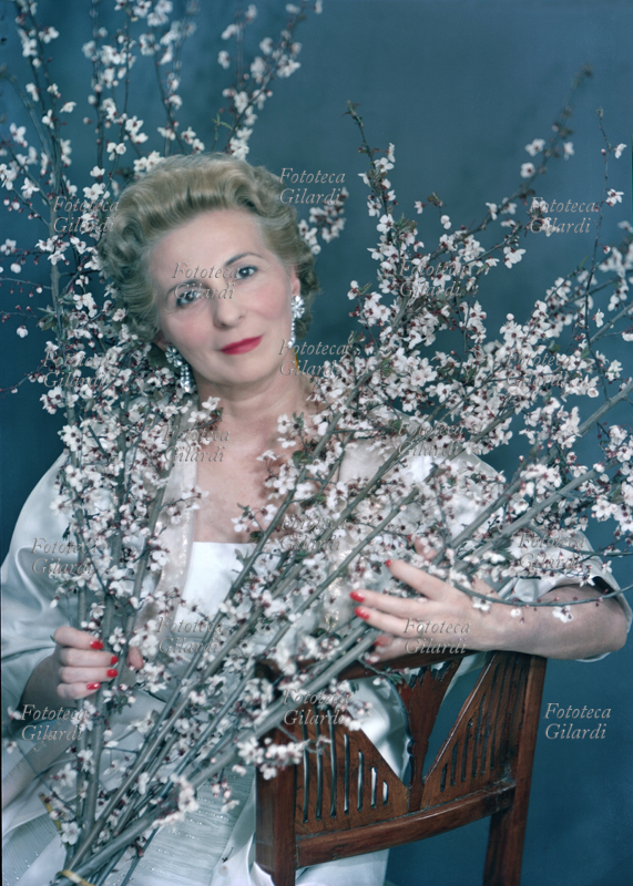 Principessa Marcella BORGHESE (15 febbraio 1911 - 19 gennaio 2002), nata Marcella Fazi, imprenditrice, fondatrice della linea cosmetica di lusso (sussidiaria della multinazionale Revlon) che porta il suo nome, seconda moglie del Principe Paolo Borghese. Ritratto fotografico seduta con ramoscelli in fiore eseguito da Ghitta Carell (20 settembre 1899 – 18 gennaio 1972), la fotografa ufficiale dei reali d\