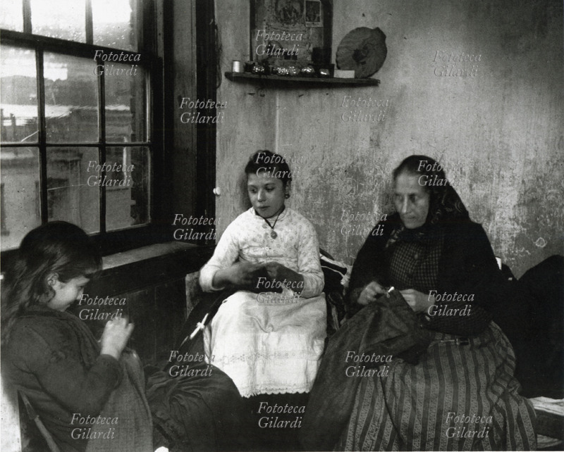 LAVORO MINORILE Bambine cuciono i pantaloni a cottimo, lavorando in famiglia con le donne di casa, per gli sfruttatori di manodopera infantile, pagate trenta centesimi al giorno. Fotografia del giornalista danese-americano Jacob A. Riis (3 maggio 1849 – 26 maggio 1914), riformatore sociale di area progressista e fotografo documentarista sociale. U.S.A. 1902.