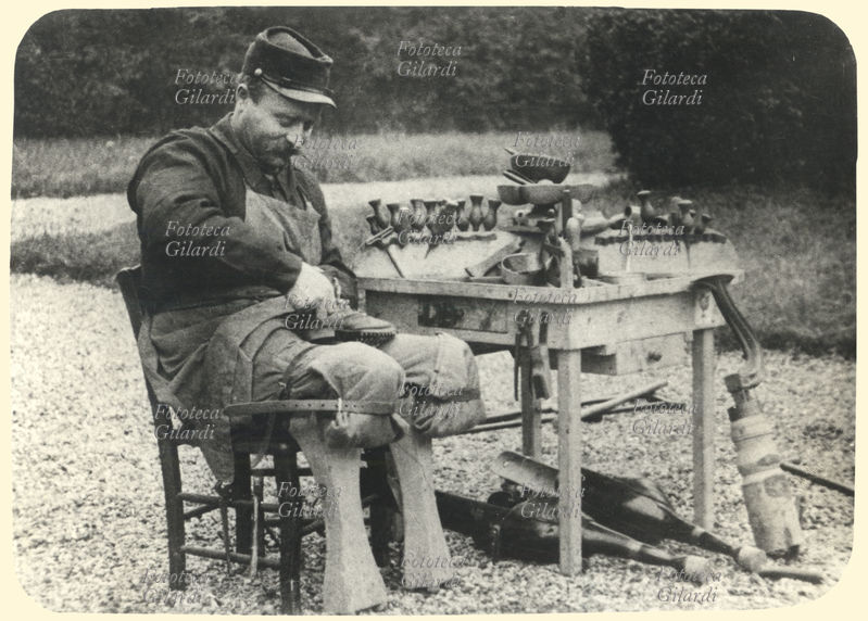 I GUERRA MONDIALE Ciabattino militare; paradossalmente, data la sua mansione, senza piedi e senza gambe. Reduce, mutilato di guerra, indossa una protesi molto rudimentale. Italia, 1918