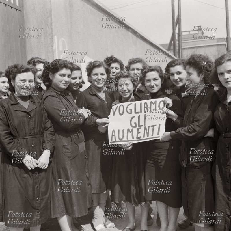 WORKERS: A picket line of young striking female workers; three of them are holding a sign that says, "We want wage increases." Madil Magnaghi Wool Mill, Via Arrivabene 4, Milan. Photograph by Ando Gilardi (1921 - 2012) #andogilardi, Milan 1954. This image is included in the series of postcards for sale here . This image is included in our photo book for sale here .