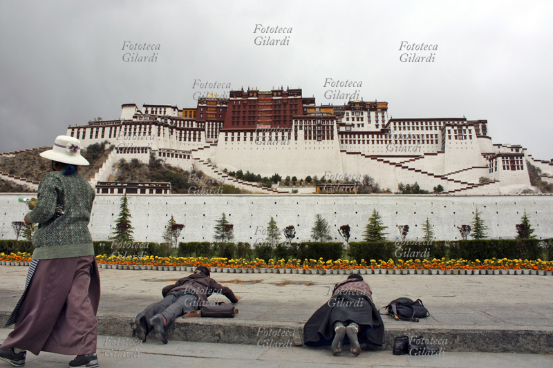 TIBET Sotto un cielo plumbeo, pellegrine buddiste si prostrano in preghiera di fronte al Potala, a Lhasa maggio 2009