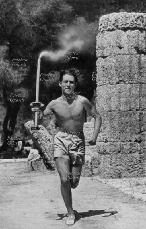 OLIMPIADI Il giovane greco Konstantin Kondylis parte con la fiaccola da Olimpia per la prima tappa dei 3000 Km da percorrere fino a Berlino. Il rito della fiamma accesa ad Olimpia e trasportata a piedi da una lunga staffetta fino al luogo delle Olimpiadi è nato con i giochi di Berlino, grazie all\