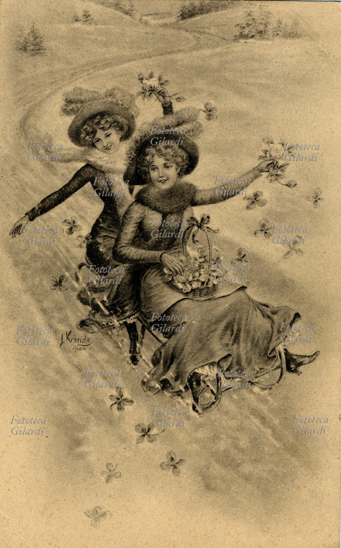 BUON NATALE due allegre giovanette in abiti invernali, lo augurano scivolando sulla neve in un unico slittino e sparpagliando nella corsa quadrifogli e rose prese da un grazioso cestino. Cartolina augurale litografica, disegno di J. Kranzle (1874 - 1937), Vienna 1915.