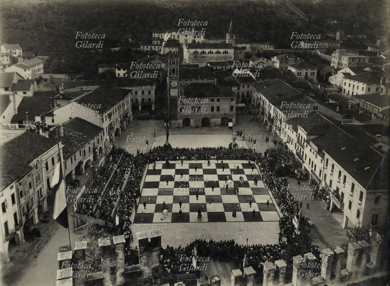SCACCHI La piazza del castello di Marostica mentre si sta svolgendo la partita sulla scacchiera gigante, antica tradizione medioevale rappresentata il secondo fine settimana del mese di settembre negli anni pari. Rara fotografia, 1920 circa. La storia della Partita risale al 1454 quando Marostica era parte della Repubblica Veneta. Due cavalieri Rinaldo d\