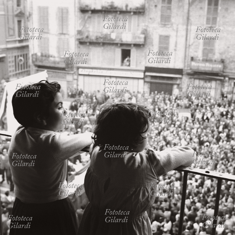 STORIA DEL MOVIMENTO OPERAIO Bambini al balcone guardano la folla radunata in piazza per la commemorazione del 60° anniversario della fondazione della Camera del Lavoro di Pavia, con il discorso di Giuseppe Di Vittorio. Fotografia di Ando Gilardi (1921 - 2012) #andogilardi, Pavia 30 giugno 1953.Questa immagine è inclusa nel nostro fotolibro in vendita qui.