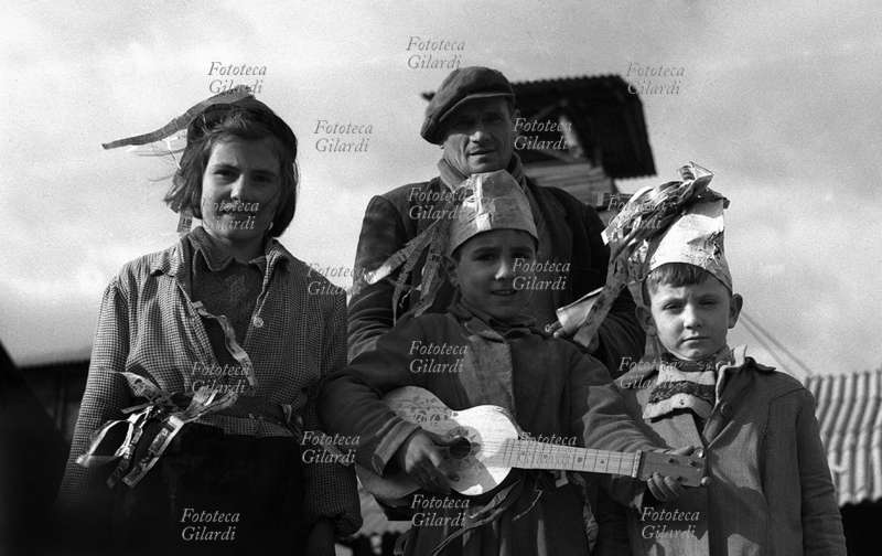BAMBINI spettacolo-festa dei figli dei minatori della storica miniera di lignite a Luni, detta la Lunara, da cui si estraeva già al tempo degli Etruschi. I bimbi portano cappelli e poveri accessori realizzati con carta di giornale. La lignite è un carbone fossile con caratteristiche di combustibile poco pregiate, entrato in disuso nel secondo dopoguerra (1950-60). Gli operai occuparono questa miniera nel tentativo di impedirne la chiusura, per non perdere il lavoro che gli permetteva di mantenere le famiglie, ma non riuscirono ad evitare la cessazione dell\