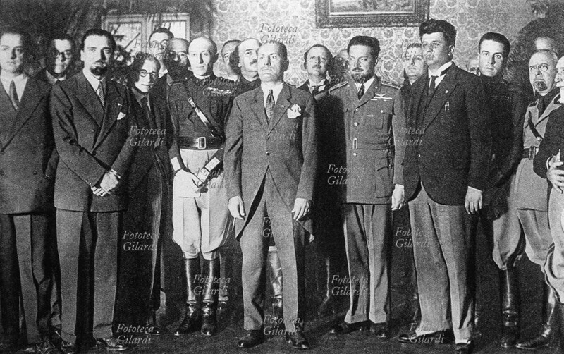 FASCISMO La prima riunione del Partito Nazionale Fascista nella nuova sede di Palazzo Vidoni. Da destra: di profilo Emilio De Bono (19 marzo 1866 – 11 gennaio 1944), Giovanni Marinelli (18 ottobre 1879 – 11 gennaio 1944), Galeazzo Ciano (18 marzo 1903 – 11 gennaio 1944), Leandro Arpinati (29 febbraio 1892 – 22 aprile 1945), Alessandro Melchiori (12 ottobre 1901 – 4 dicembre 1987), Italo Balbo (6 giugno 1896 – 28 giugno 1940), Riccardi, Benito Mussolini (29 luglio 1883 – 28 aprile 1945), Costanzo Ciano (30 agosto 1876 – 26 giugno 1939), Augusto Turati (25 agosto 1888 – 27 agosto 1955), due persone non identificate, Michele Bianchi (22 luglio 1883 – 3 febbraio 1930), Dino Grandi (4 giugno 1895 – 21 maggio 1988), Ferri, Giuseppe Bottai (3 settembre 1895 – 9 gennaio 1959). Italia, 1929.