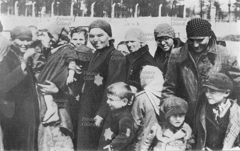 II GM NAZISMO donne e bambini avviati alla morte dopo la selezione, sullo sfondo i reticolati. Auschwitz era un campo di lavoro e di sterminio: appena arrivati venivano selezionati i soggetti utili al lavoro gli altri venivano eliminati. In genere vecchi e bambini erano considerati inutili, era poi molto difficile separare i bambini piccoli dalle madri. Polonia, 1941.