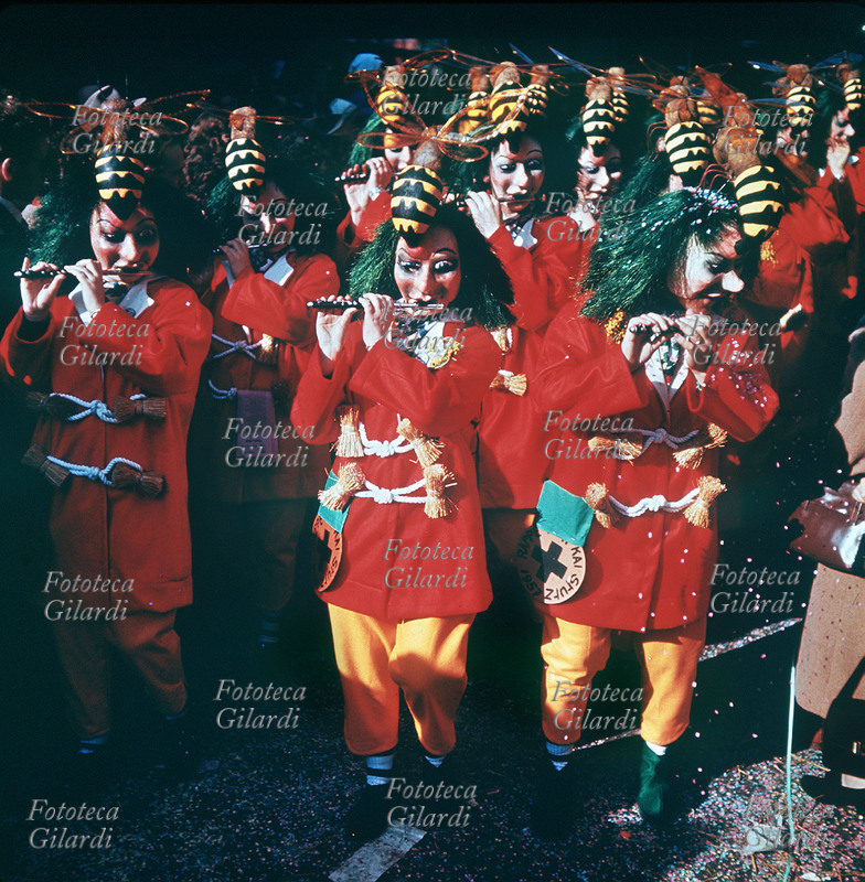 CARNEVALE a Basilea, la parata di una delle numerosissime bande di ottavini, mascherati in livrea rossa e gialla, con capelli verdi e grossi calabroni sul capo. Svizzera, 1957.