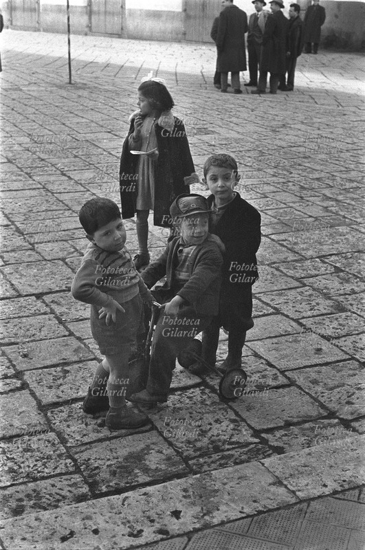 ITALIA S.M.O. Venosa, bambini in Piazza Orazio. Fotografia di Ando Gilardi (1921-2012) #andogilardi, parte di un ampio servizio realizzato per \