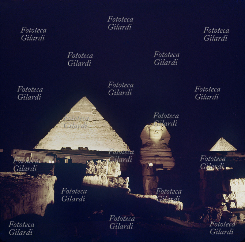 PIRAMIDI DI GIZAH Gizah è uno dei maggiori siti archeologici in Egitto: suggestiva veduta notturna delle piramidi e della sfinge. Il gruppo delle piramidi di Cheope, Kefren e Micerino si suppone siano state edificate attorno al 2800 a.C. Mentre usualmente si fa risalire la Sfinge, scavata direttamente nella roccia e i due arcaici templi a essa connessi al 2.500 circa a.C.; la loro paternità è attribuita al faraone Chefren in base a una lapide recante il suo nome rinvenuta sul posto. Fotografia, 1980 circa.