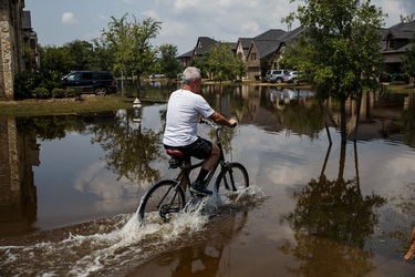September 2, 2017 - Fort Bend County, Texas, United States: A man cycles through floodwater in the aftermath of tropical storm Harvey, in the Millwood subdivision of Fort Bend County. (Marcus Yam / Los Angeles Times/Polaris)
