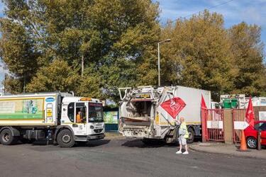 Pic by Luke Johnston / Caters News (PICTURED: Bin men return with their trucks and are waved in by another bin man with a flag) - Around 40 bin men stood outside the gates of their waste depot in protest of lost jobs. Unite the union flags were being waved on Friday morning by refuse collectors after Birmingham City Council announced it was handing out redundancy notices to dustmen. Furious worked pulled up outside the gates to Perry Barr Household Waste and Recycling Centre in Birmingham honking their truck horns. The strike which left much of Birmingham covered in bin bags and maggots over the Summerresumed at 7.30am this morning with Unite union saying it will now reballot workers and industrial action could last until 2018. ENDS
