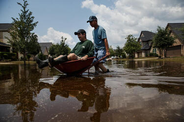September 2, 2017 - Fort Bend County, Texas, United States: Lung Hui Chen pushes Manuel Terrazas in a wheel barrel across flooded streets as local residents clear out homes damaged in the aftermath of tropical storm Harvey, in the Millwood subdivision of Fort Bend County. (Marcus Yam / Los Angeles Times/Polaris)