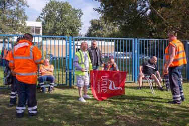 Pic by Luke Johnston / Caters News (PICTURED: Bin Men gathered outside of the Perry Barr Household Recycling Centre) - Around 40 bin men stood outside the gates of their waste depot in protest of lost jobs. Unite the union flags were being waved on Friday morning by refuse collectors after Birmingham City Council announced it was handing out redundancy notices to dustmen. Furious worked pulled up outside the gates to Perry Barr Household Waste and Recycling Centre in Birmingham honking their truck horns. The strike which left much of Birmingham covered in bin bags and maggots over the Summerresumed at 7.30am this morning with Unite union saying it will now reballot workers and industrial action could last until 2018. ENDS