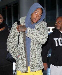 Wiz Khalifa heads through LAX with his entourage. The rapper wears colorful layers and tops off his look with a leopard print jacket. Friday, November 18, 2016 X17online.com