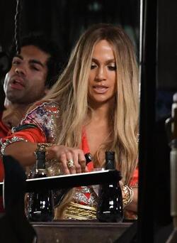 Jennifer Lopez wears a low cut red wrap dress with shimmering gold sequins as she is seen filming a music video