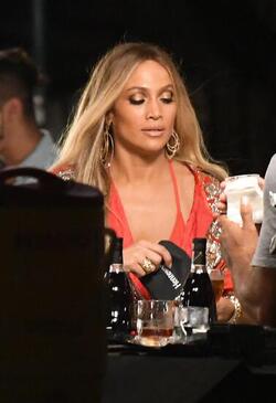 Jennifer Lopez wears a low cut red wrap dress with shimmering gold sequins as she is seen filming a music video