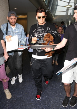 Orlando Bloom returned to Los Angeles carrying his puppy and signing autographs on his way to his waiting vehicle.